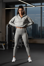 Woman in gray athletic outfit posing in a gym with cityscape view | From Me Fitness Apparel