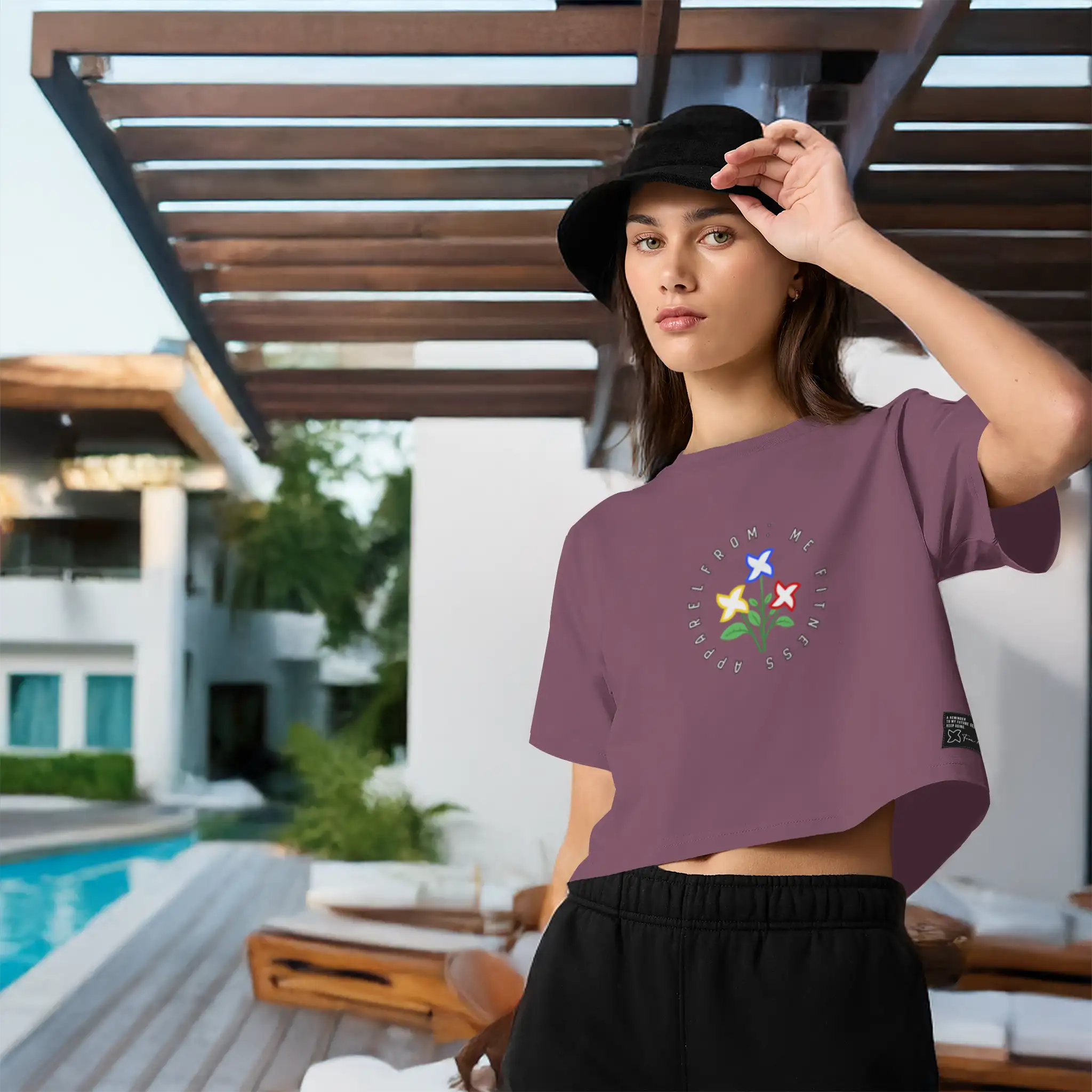 Woman wearing a purple t-shirt with a colorful design outdoors by a pool