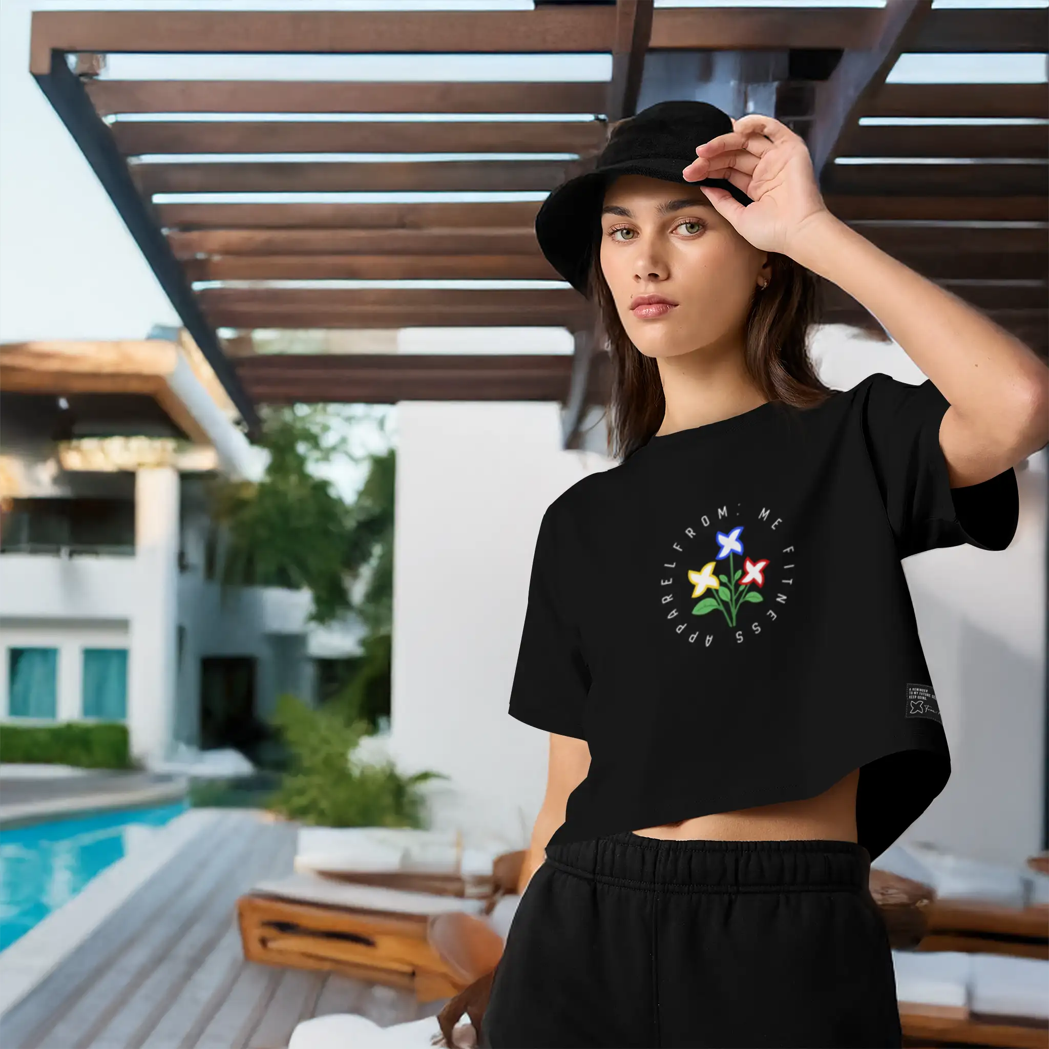 Woman wearing a black t-shirt with a colorful design outdoors by a pool
