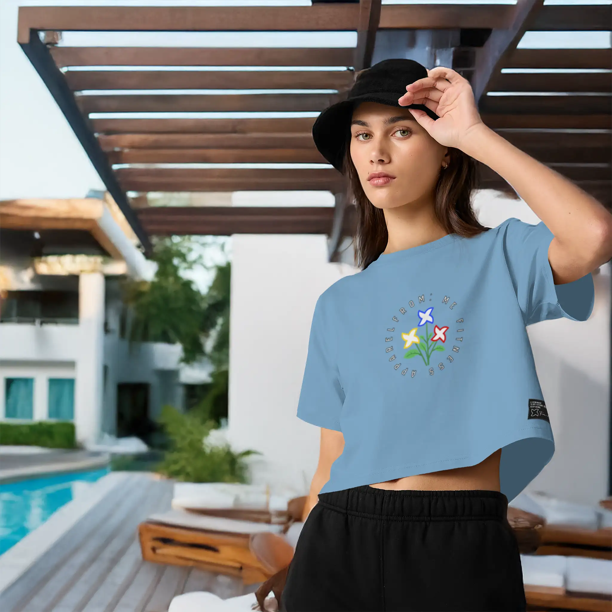 Woman wearing a blue t-shirt with a floral design by a poolside | From Me Fitness Apparel