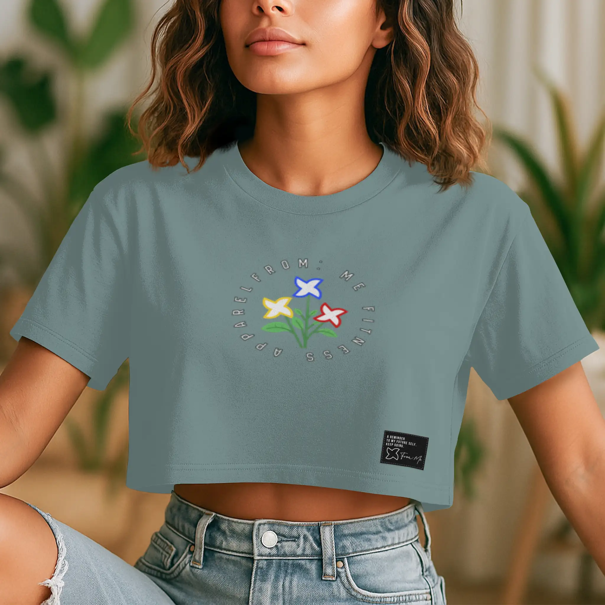 Person wearing a light blue crop top with floral design and brand logo.