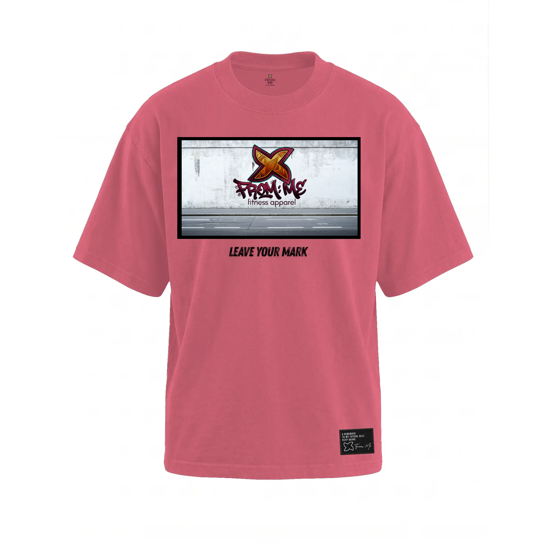 A pink short-sleeve t-shirt with a rectangular graphic print on the chest featuring a graffiti-style orange logo and the text 'From Me Fitness Apparel' and 'LEAVE YOUR MARK'. A small black brand patch is visible on the lower right hem.