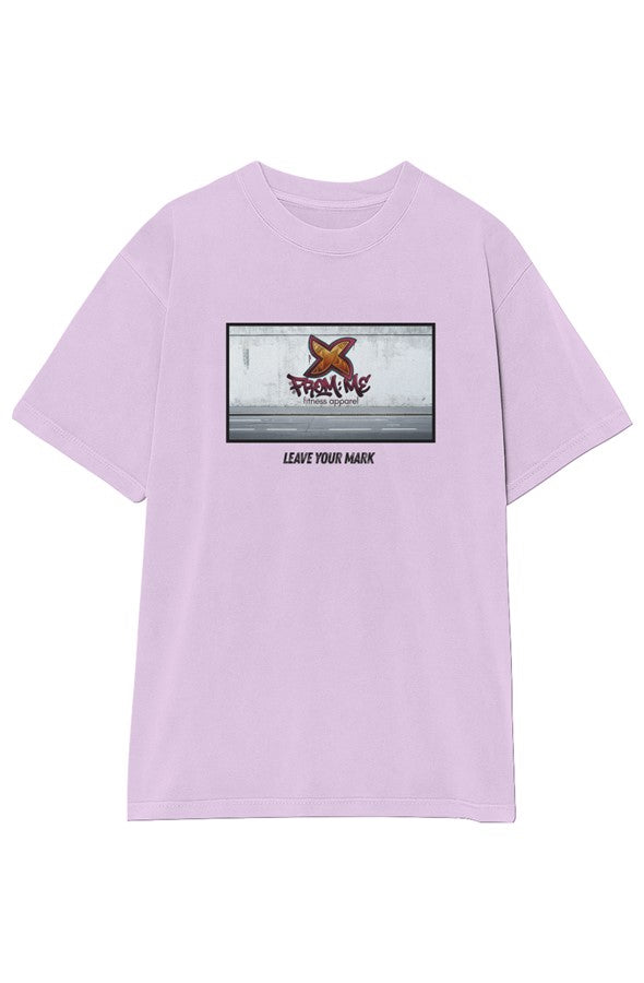 A purple short-sleeve t-shirt with a rectangular graphic print on the chest featuring a graffiti-style orange logo and the text 'From Me Fitness Apparel' and 'LEAVE YOUR MARK'. A small black brand patch is visible on the lower right hem.