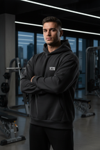 Man wearing a black hoodie with a lifting club logo in a gym setting | From Me Fitness Apparel